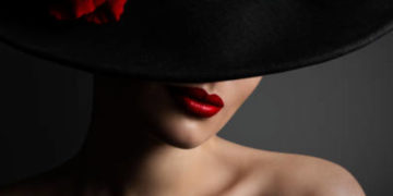 Woman Red Lips and Rose Flower in Hat, Fashion Model Beauty Portrait, Black Retro Wide Brimmed Hat over black studio background